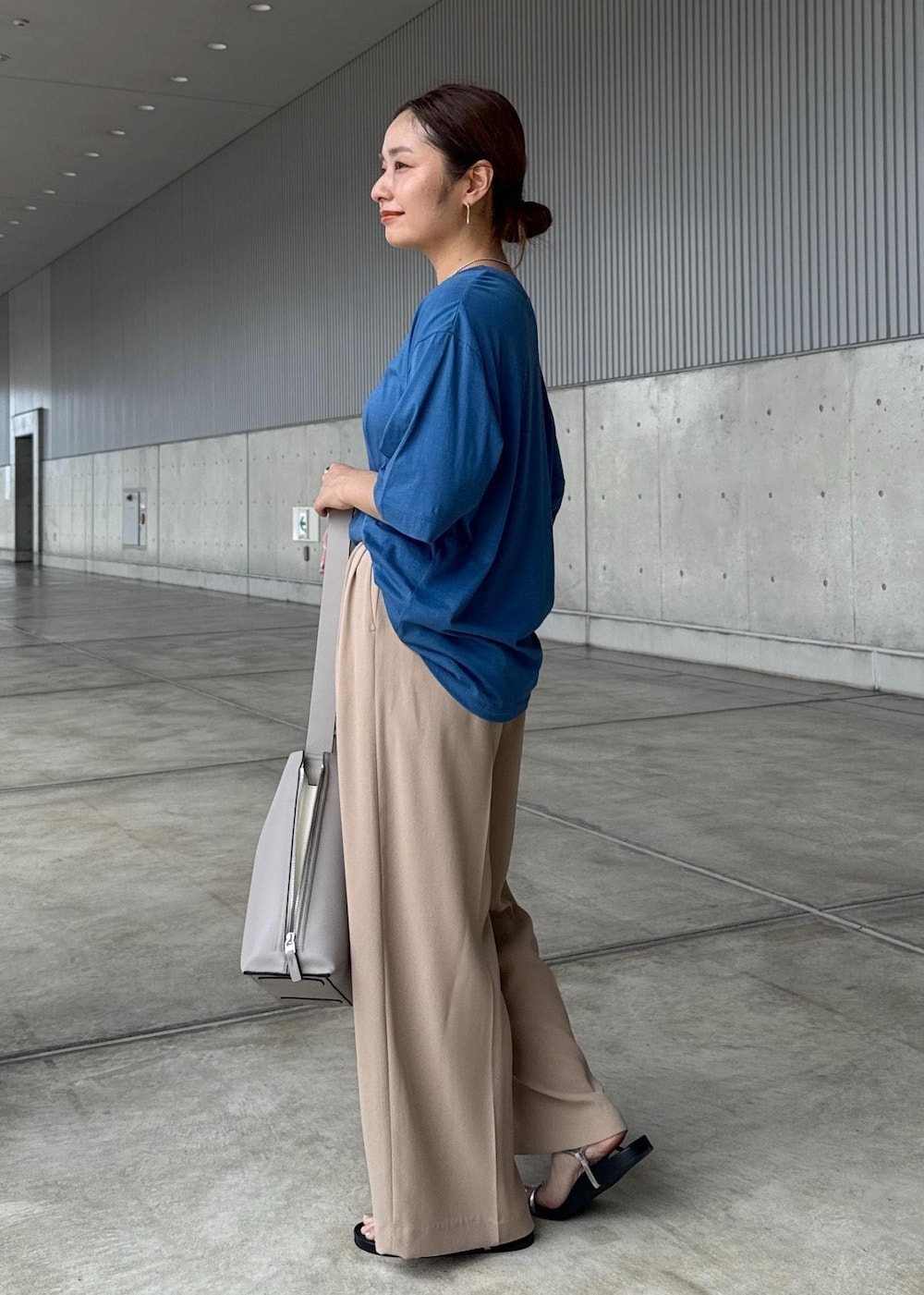 グレー系のショルダーバッグ、シルバー系のサンダル、ブルー系のTシャツ/カットソーを着用したレディースの夏コーディネートの2枚目の写真