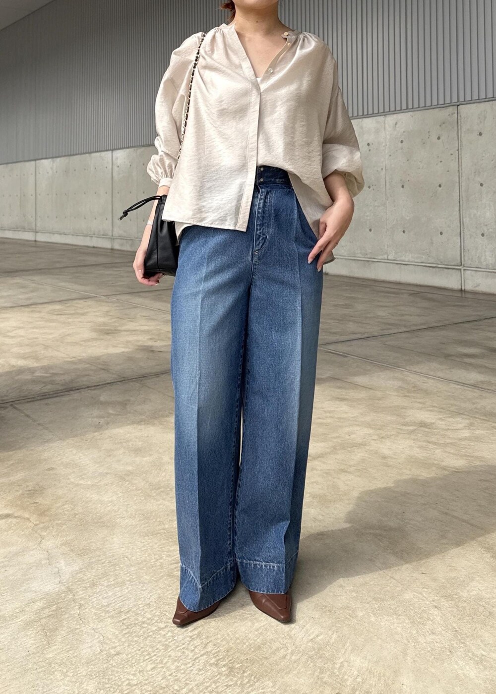 ブルー系のデニムパンツ、ブラック系のハンドバッグ、ベージュ系のシャツ/ブラウスを着用したレディースの春コーディネートの7枚目の写真