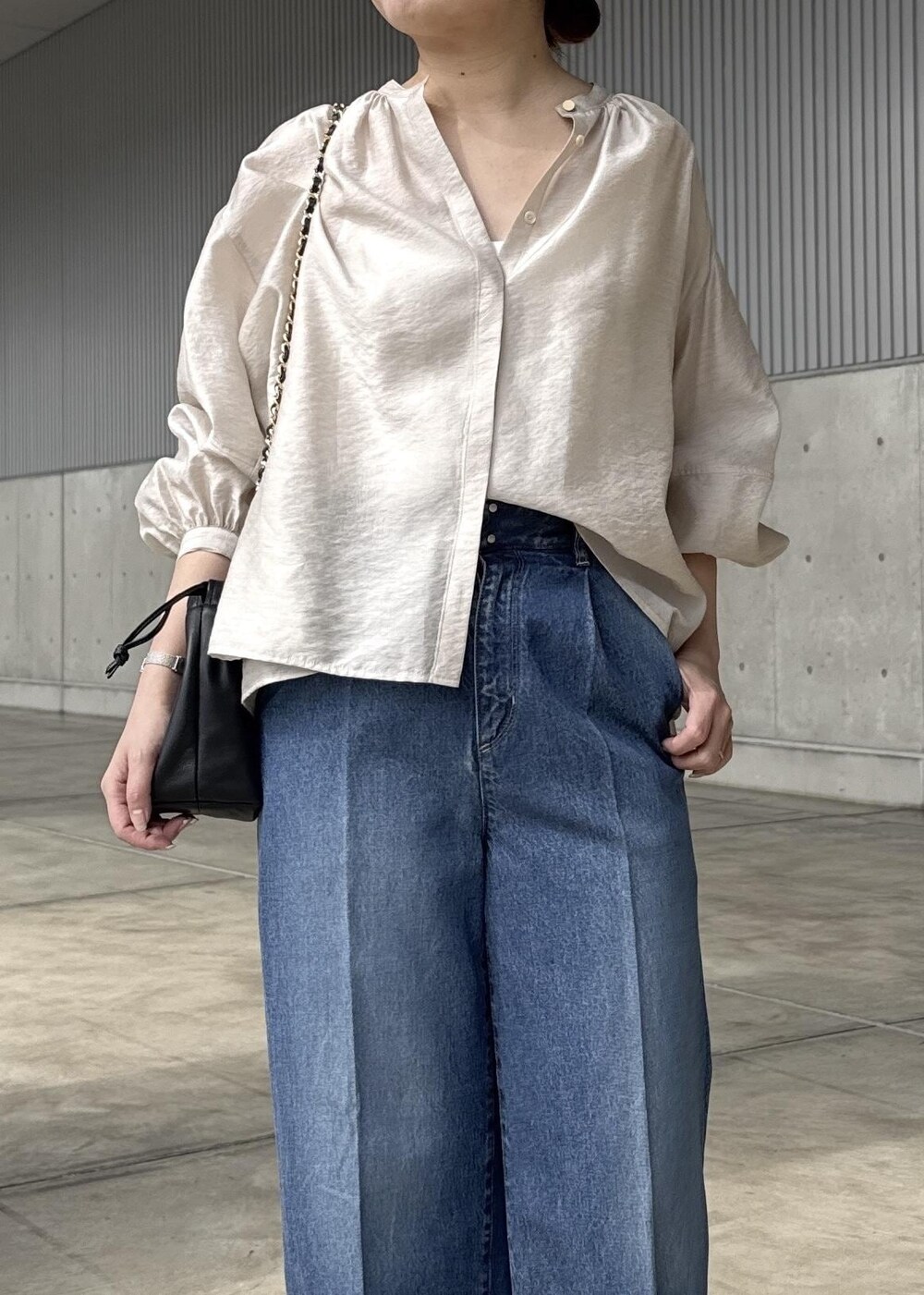 ブルー系のデニムパンツ、ブラック系のハンドバッグ、ベージュ系のシャツ/ブラウスを着用したレディースの春コーディネートの4枚目の写真