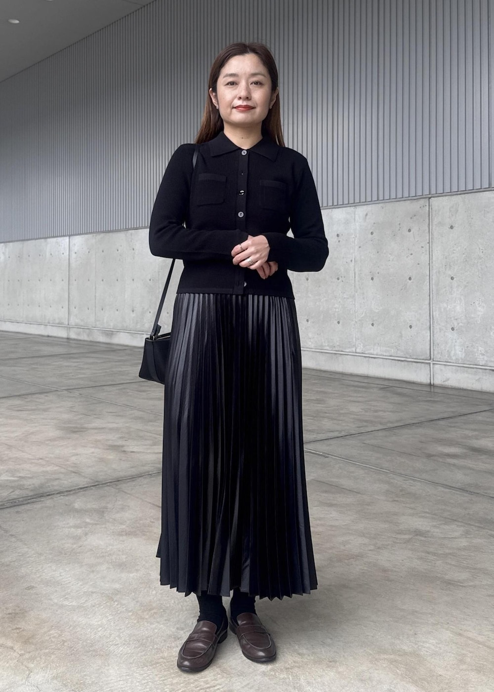 ブラック系のスカート、ブラック系のショルダーバッグ、ベージュ系のトレンチコートを着用したレディースの春コーディネートの2枚目の写真