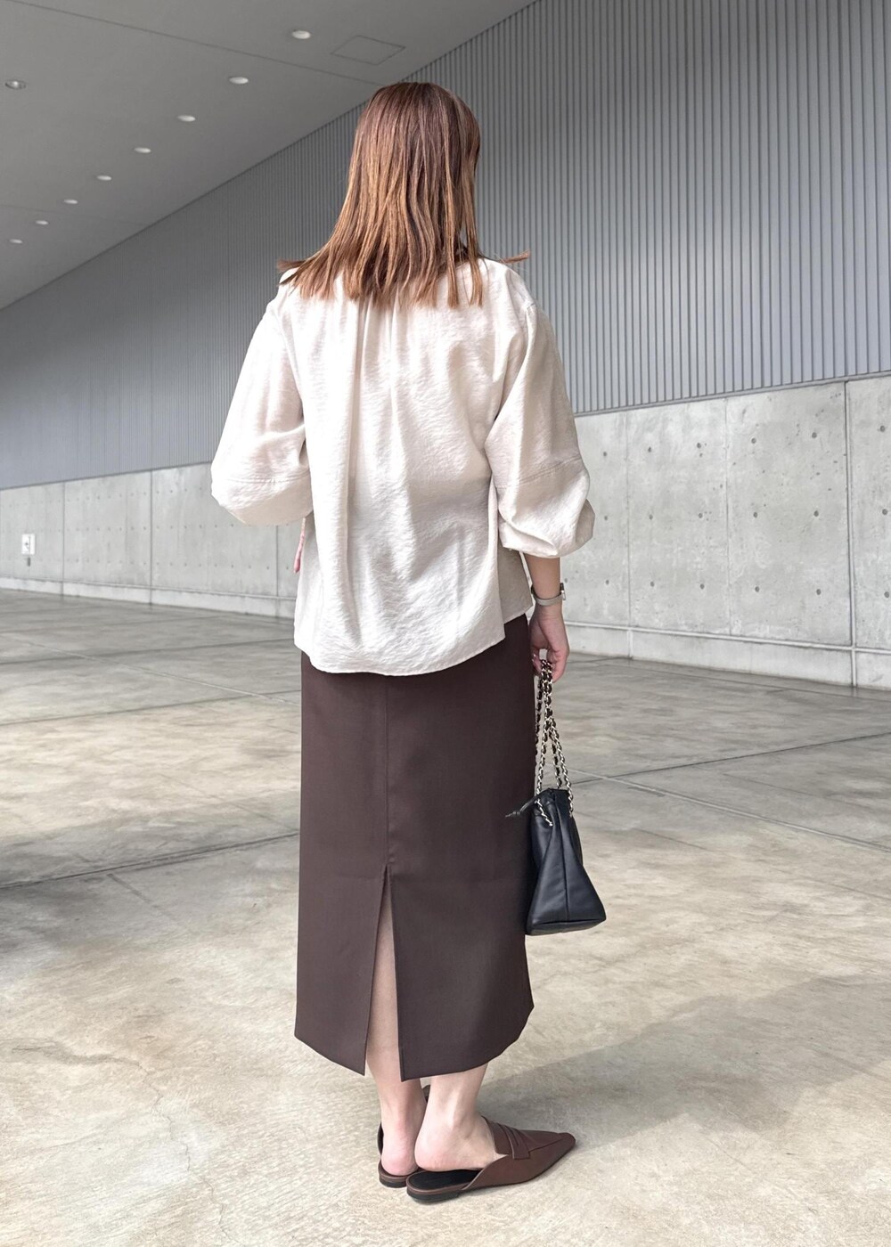 ブラック系のハンドバッグ、ブラウン系のスカート、ベージュ系のシャツ/ブラウスを着用したレディースの春コーディネートの8枚目の写真