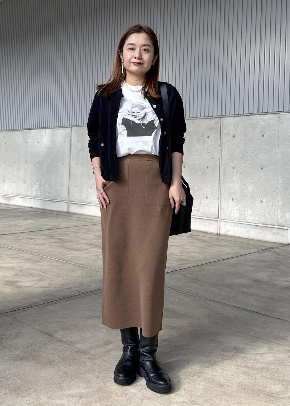 ブラウン系のスカート、ブラック系のカーディガン/ボレロ、ホワイト系のTシャツ/カットソーを着用したレディースの冬コーディネートの5枚目の写真