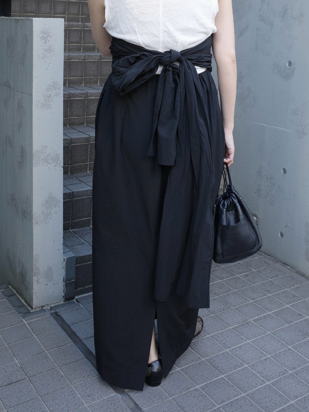 ブラック系のスカート、ホワイト系のショルダーバッグ、ブラック系のパンプスを着用したレディースの秋コーディネートの2枚目の写真