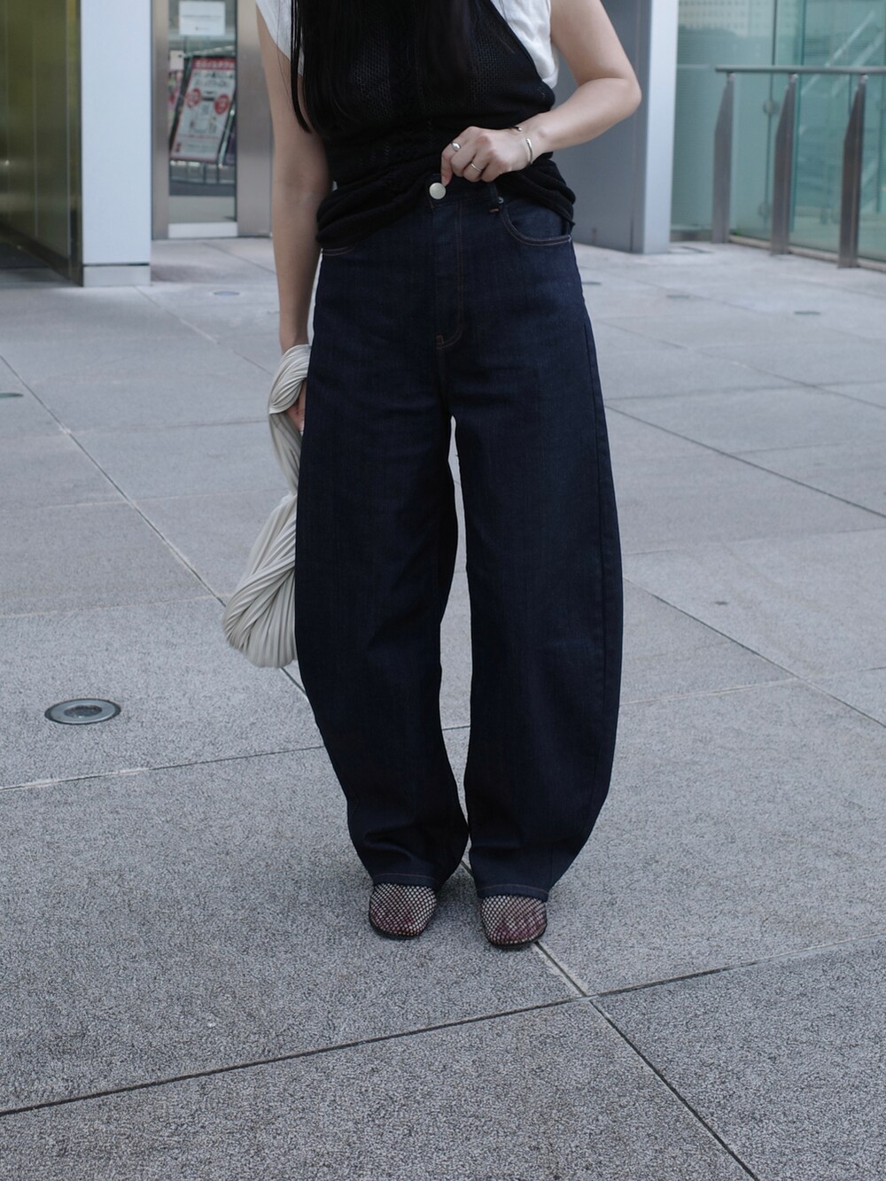 ブラック系のキャミソール、ブルー系のデニムパンツ、ブラック系のパンプスを着用したレディースの秋コーディネートの4枚目の写真
