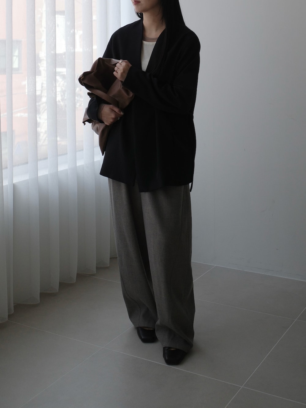 ベージュ系のスラックス、ブラック系のその他アウター、ベージュ系のバッグを着用したレディースの秋コーディネートの4枚目の写真