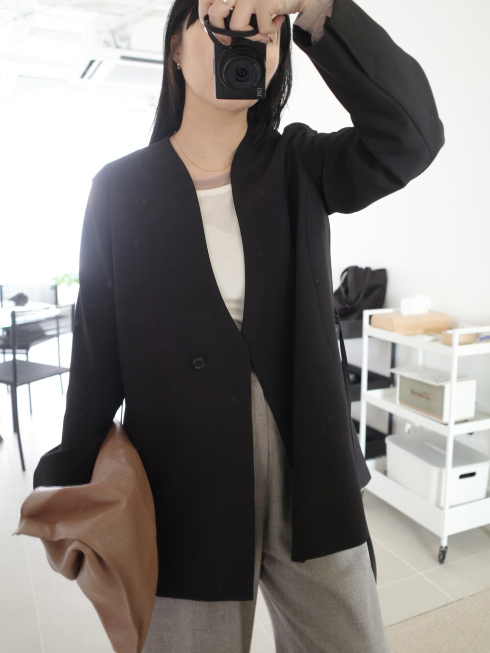 ベージュ系のスラックス、ブラック系のその他アウター、ベージュ系のバッグを着用したレディースの秋コーディネートの5枚目の写真