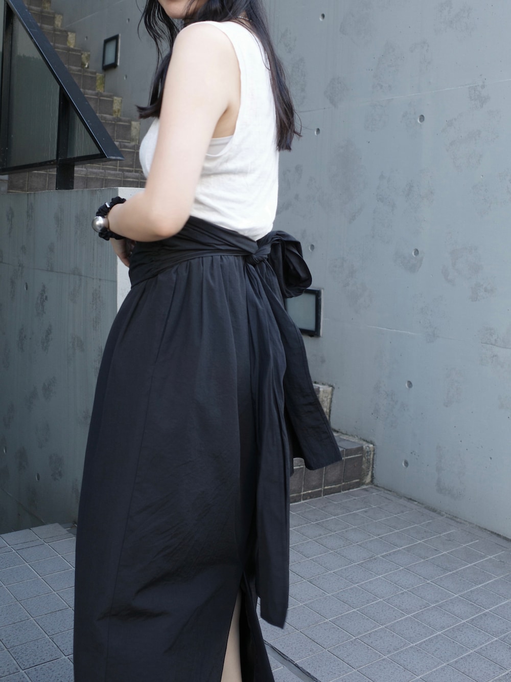 ブラック系のスカート、ホワイト系のショルダーバッグ、ブラック系のパンプスを着用したレディースの秋コーディネートの5枚目の写真