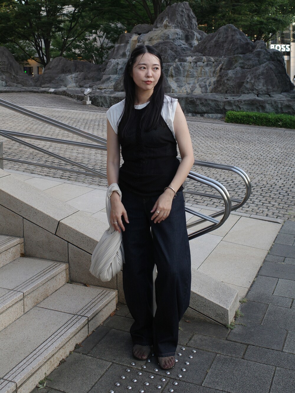 ブラック系のキャミソール、ブルー系のデニムパンツ、ブラック系のパンプスを着用したレディースの秋コーディネートの2枚目の写真