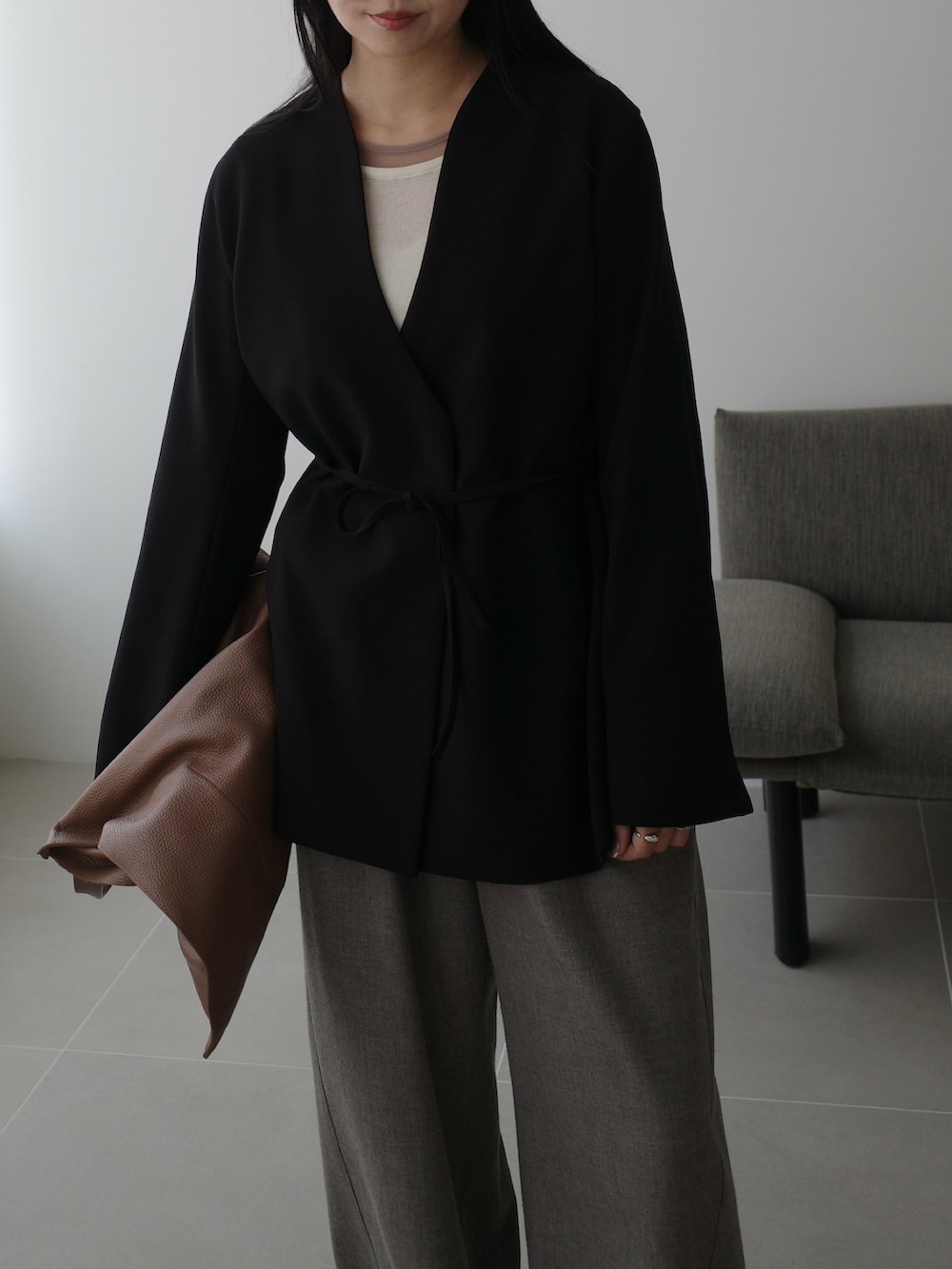 ベージュ系のスラックス、ブラック系のその他アウター、ベージュ系のバッグを着用したレディースの秋コーディネートの3枚目の写真