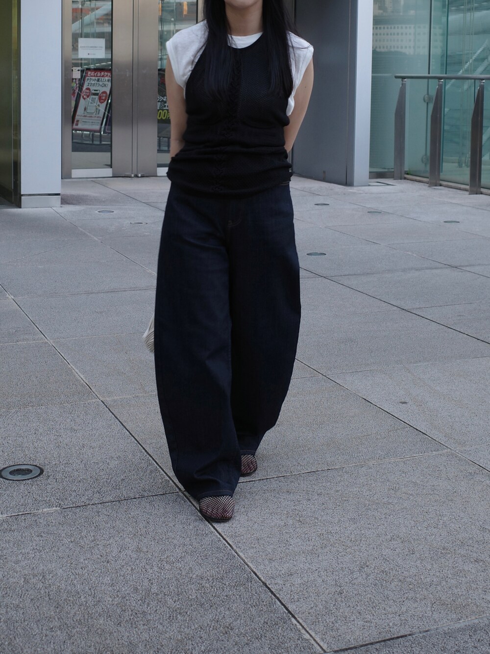 ブラック系のキャミソール、ブルー系のデニムパンツ、ブラック系のパンプスを着用したレディースの秋コーディネートの3枚目の写真