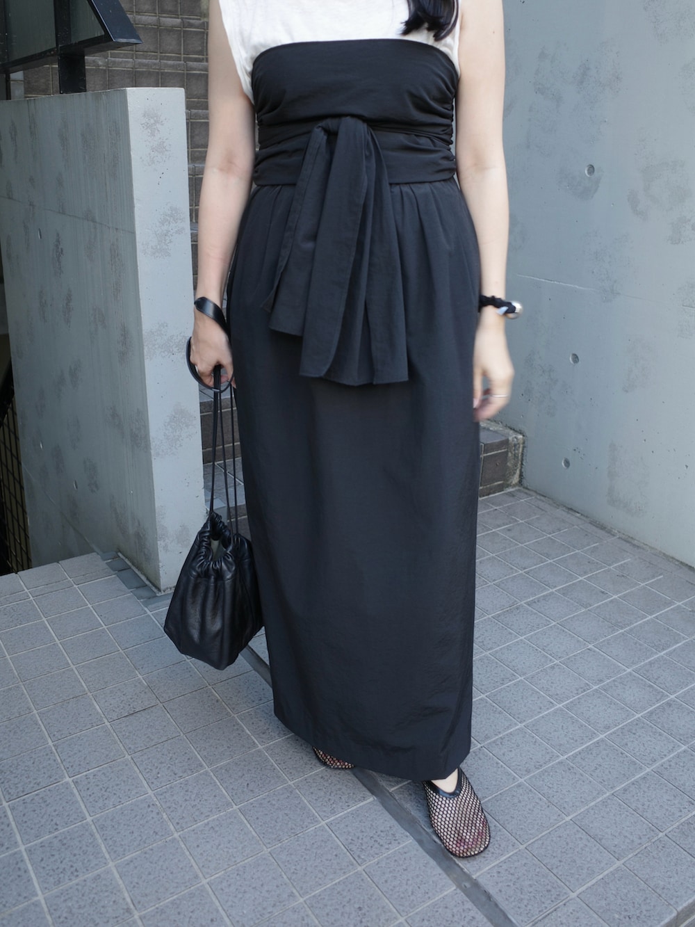 ブラック系のスカート、ホワイト系のショルダーバッグ、ブラック系のパンプスを着用したレディースの秋コーディネートの3枚目の写真