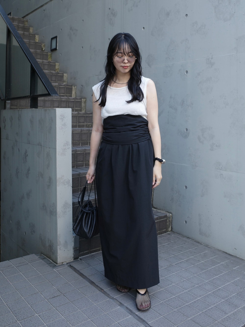 ブラック系のスカート、ホワイト系のショルダーバッグ、ブラック系のパンプスを着用したレディースの秋コーディネートの4枚目の写真