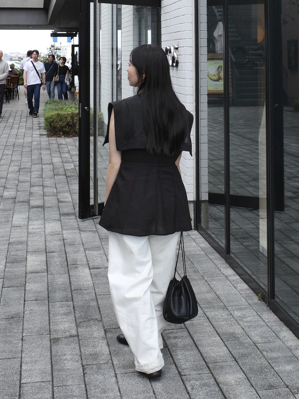 ホワイト系のショルダーバッグ、ホワイト系のデニムパンツ、ブラック系のシャツ/ブラウスを着用したレディースの秋コーディネートの2枚目の写真