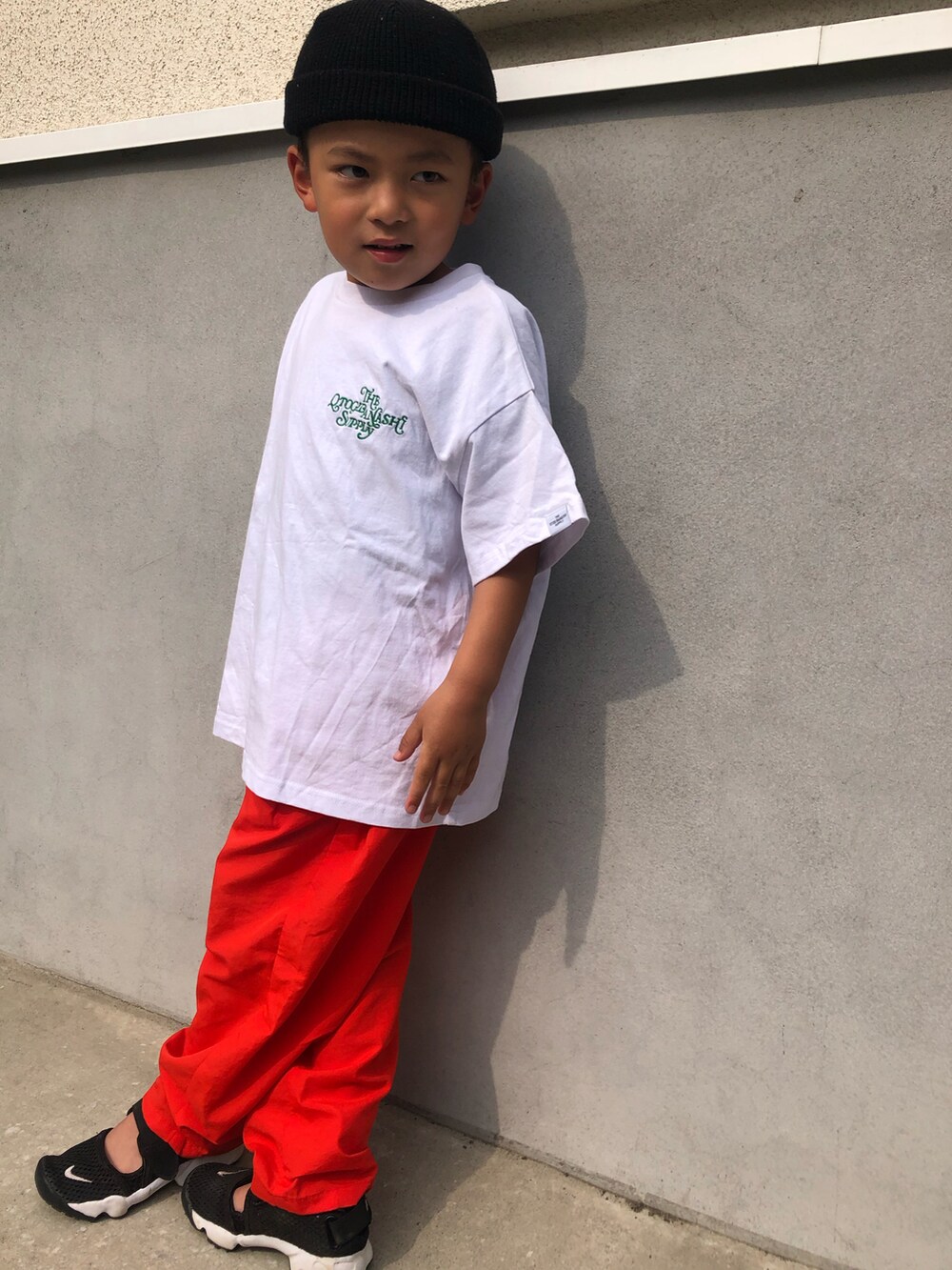 ホワイト系のTシャツ/カットソー、レッド系のその他パンツ、ブラック系のサンダルを着用したキッズの春コーディネートの2枚目の写真