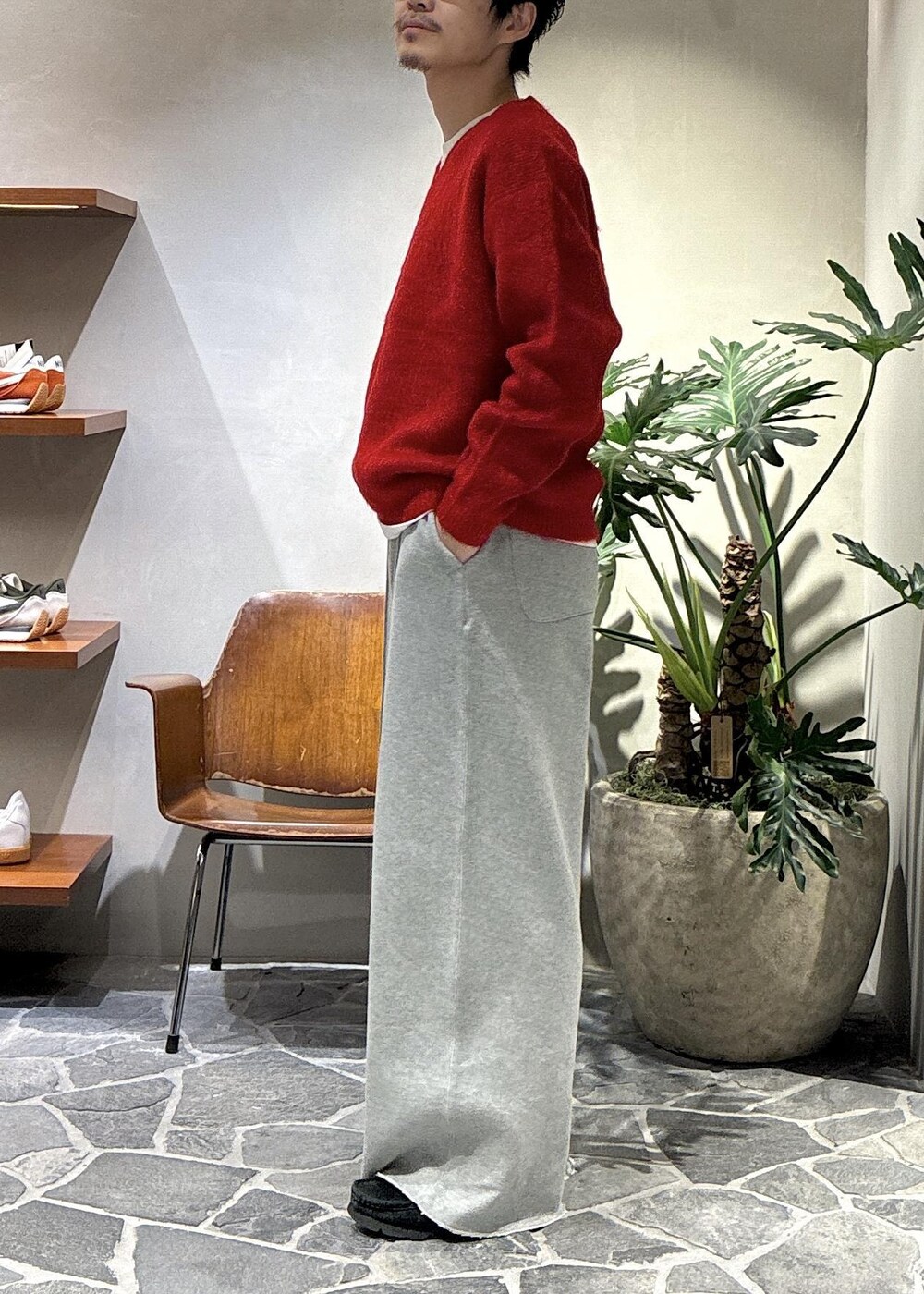レッド系のニット/セーター、グレー系のその他パンツを着用したメンズの秋コーディネートの4枚目の写真