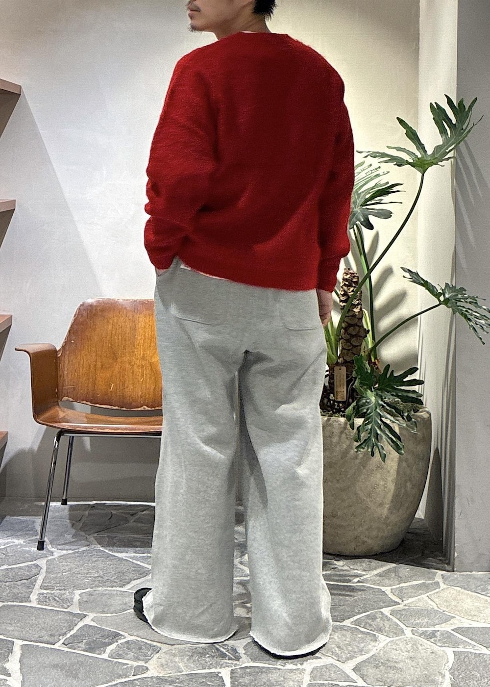 レッド系のニット/セーター、グレー系のその他パンツを着用したメンズの秋コーディネートの5枚目の写真