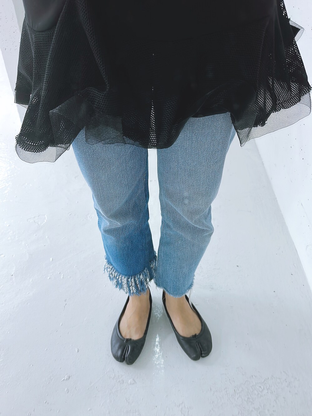ブルー系のデニムパンツ、ブラック系のトップス、ブラック系のシューズを着用したレディースの秋コーディネートの2枚目の写真