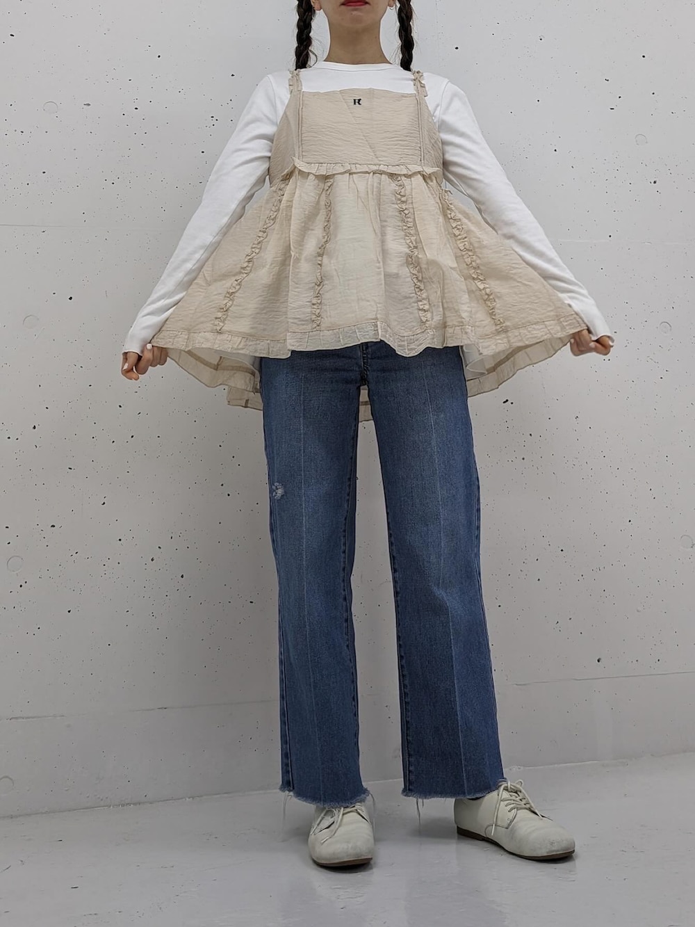 ベージュ系のキャミソール、ブルー系のデニムパンツを着用したレディースの春コーディネートの2枚目の写真