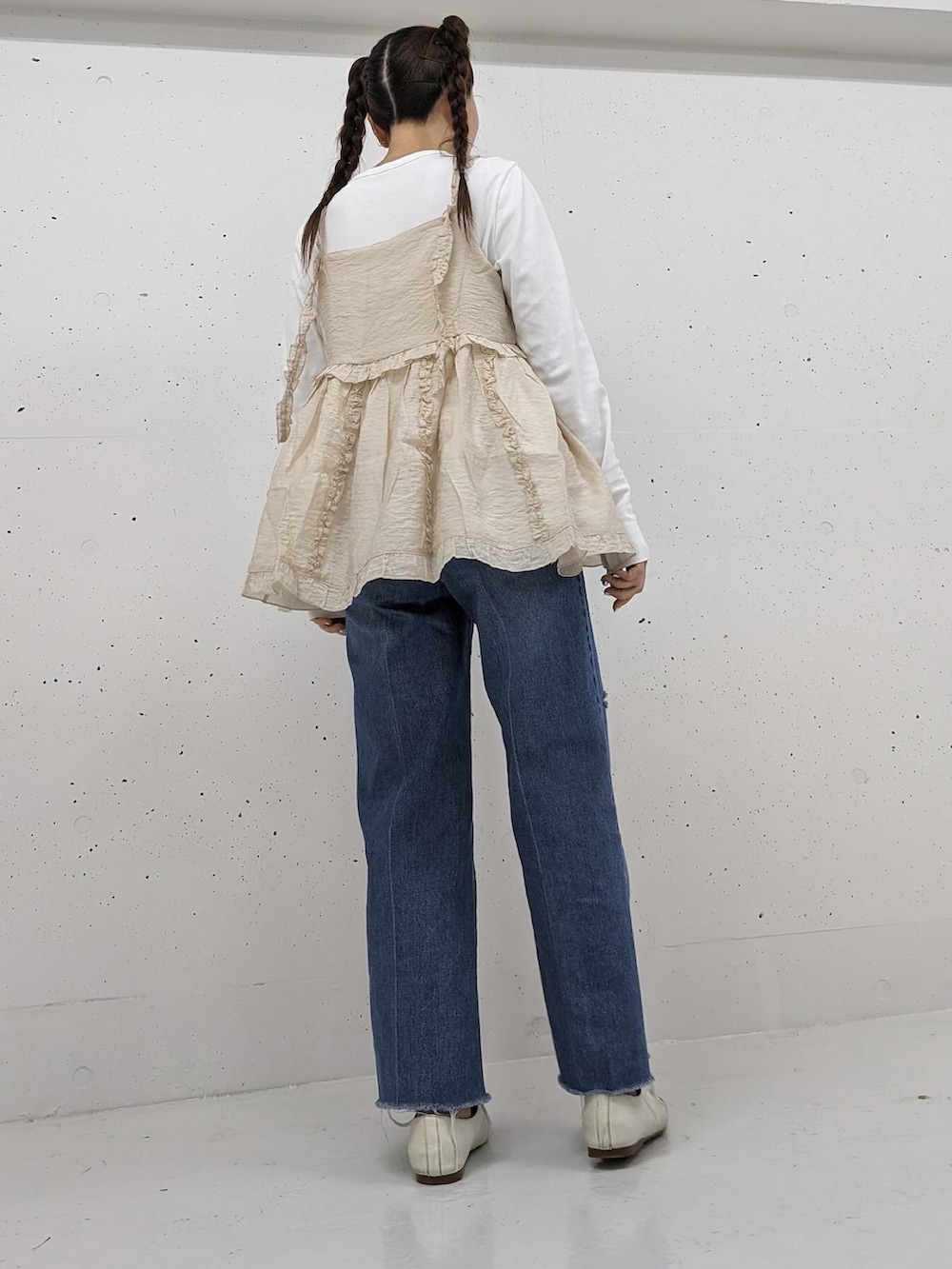 ベージュ系のキャミソール、ブルー系のデニムパンツを着用したレディースの春コーディネートの3枚目の写真