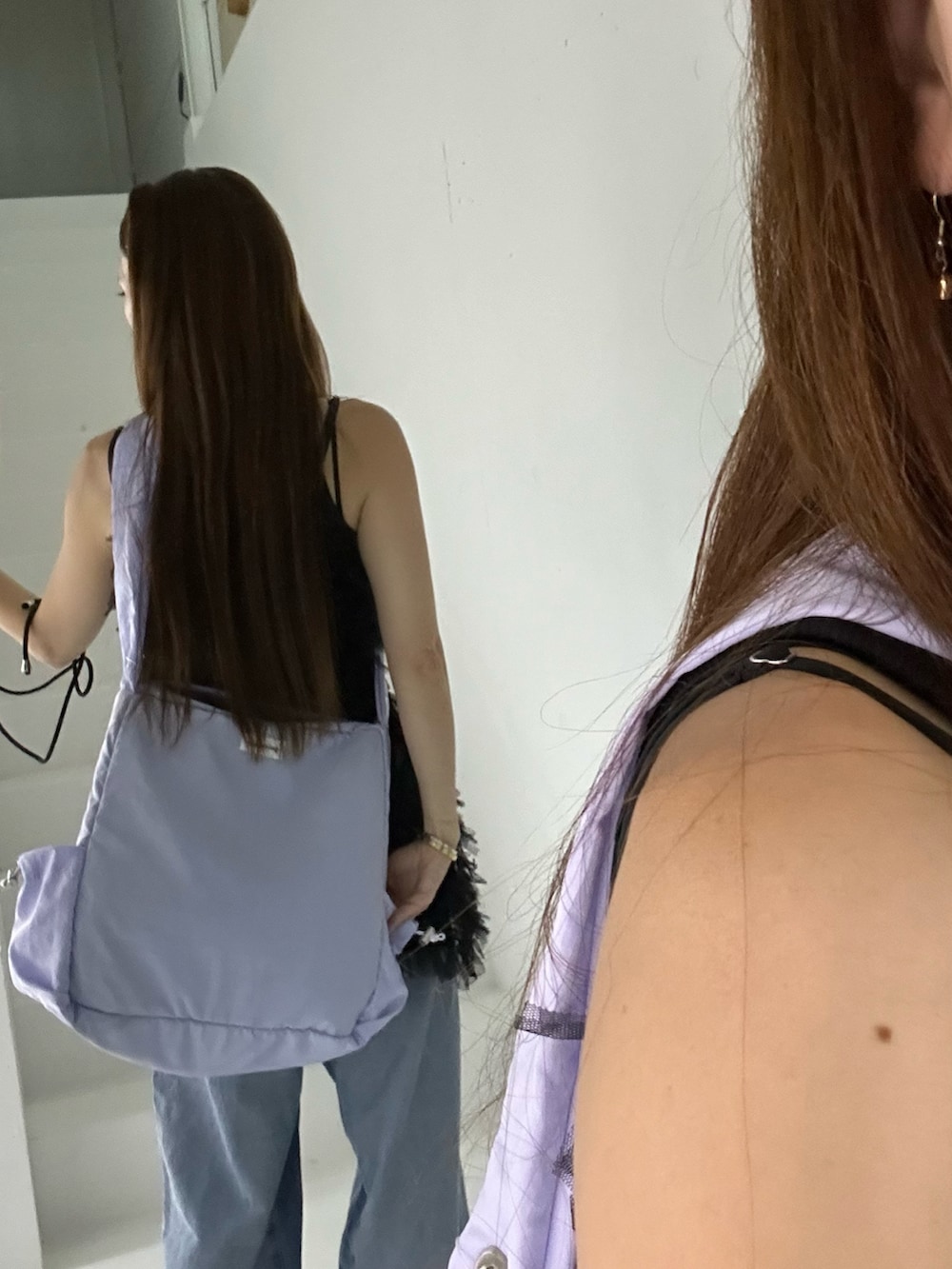 パープル系のショルダーバッグ、ブルー系のデニムパンツ、ブラック系のキャミソールを着用したレディースの夏コーディネートの2枚目の写真