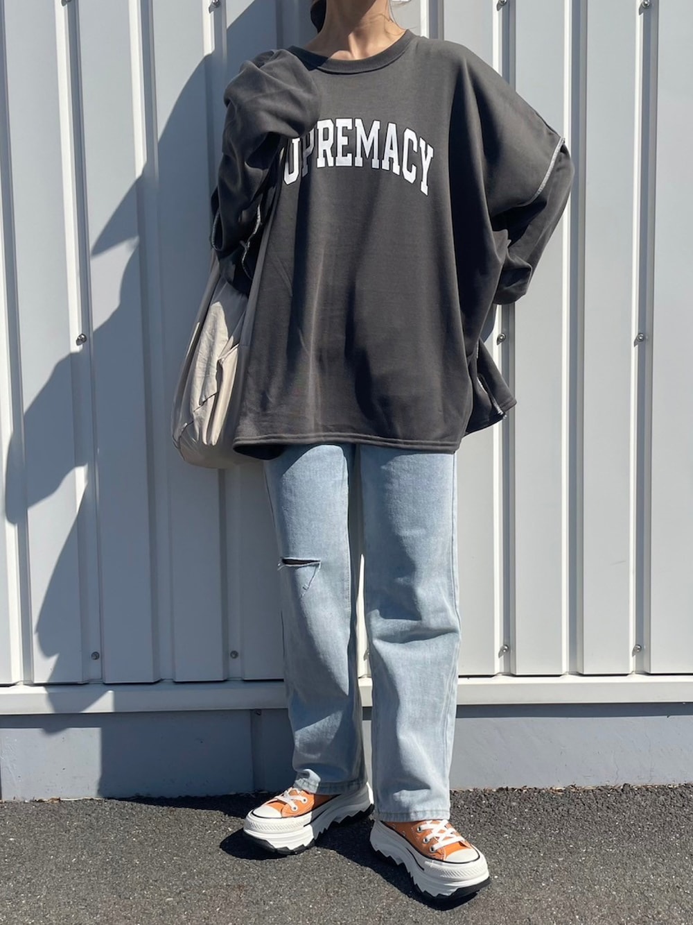 グレー系のスウェット、ブルー系のデニムパンツ、ホワイト系のバックパック/リュックを着用したレディースの春コーディネートの2枚目の写真