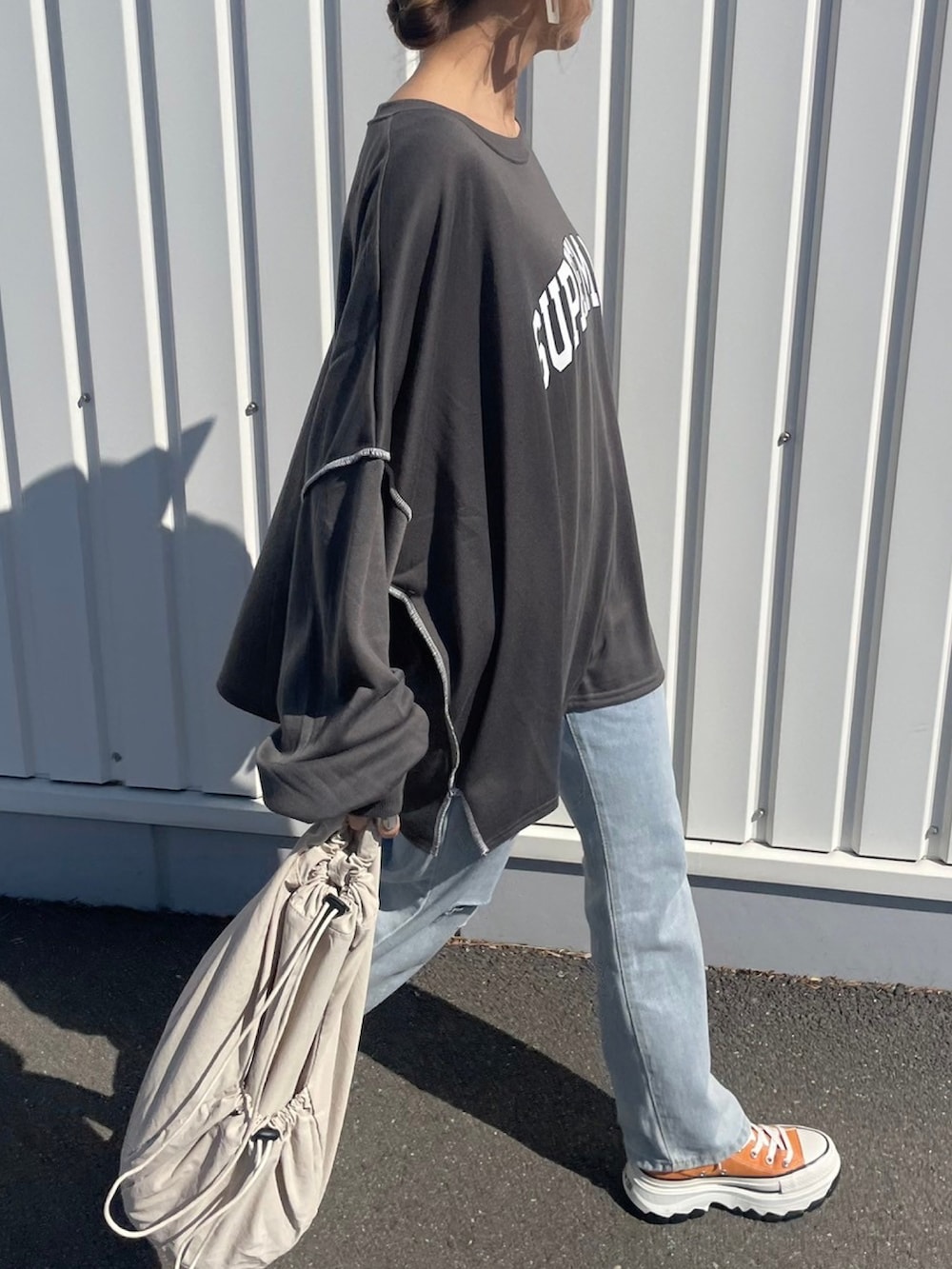 グレー系のスウェット、ブルー系のデニムパンツ、ホワイト系のバックパック/リュックを着用したレディースの春コーディネートの4枚目の写真