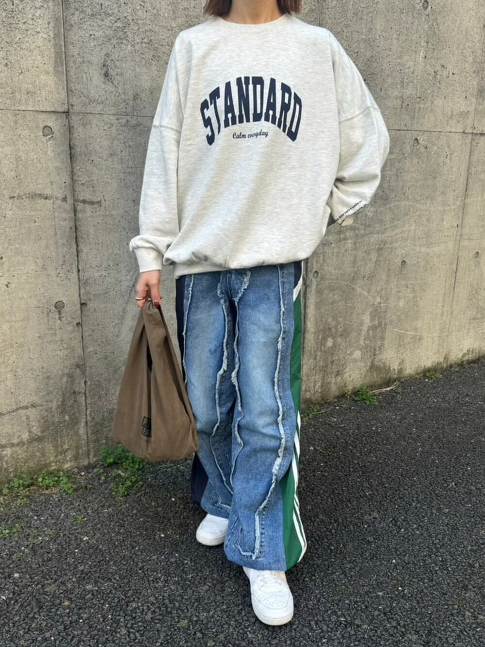 グレー系のスウェット、ブルー系のデニムパンツ、ホワイト系のスニーカーを着用したレディースの冬コーディネートの2枚目の写真