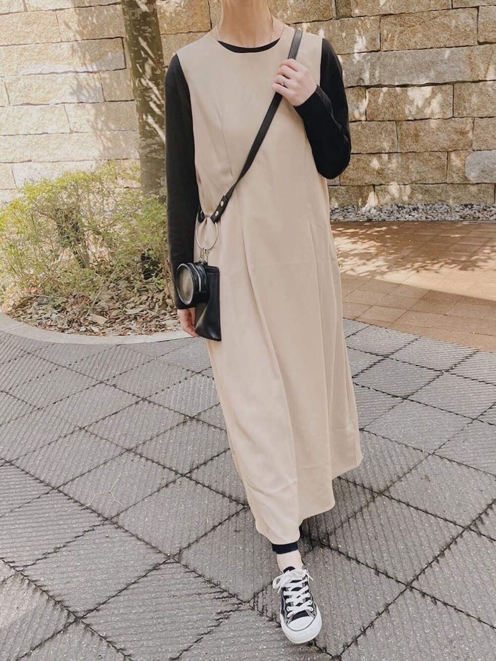 ベージュ系のワンピース、ブラック系のTシャツ/カットソー、ブラック系のスニーカーを着用したレディースの春コーディネートの2枚目の写真