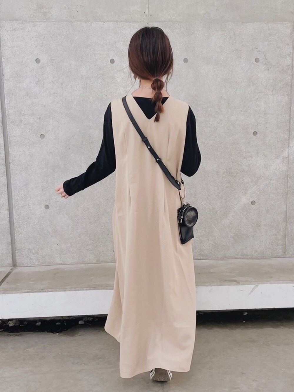 ベージュ系のワンピース、ブラック系のTシャツ/カットソー、ブラック系のスニーカーを着用したレディースの春コーディネートの4枚目の写真