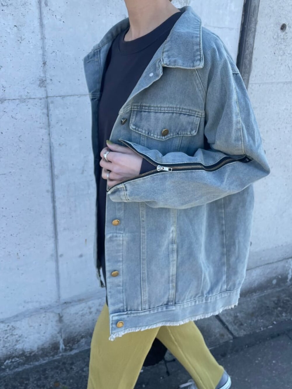 ブルー系のデニムジャケット、ブラック系のメッセンジャーバッグ、グレー系のスニーカーを着用したレディースの春コーディネートの4枚目の写真