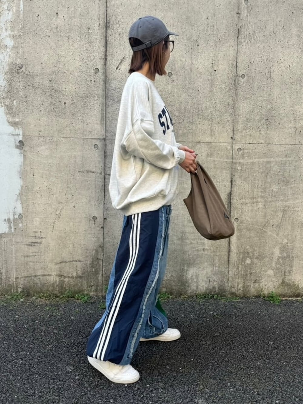 グレー系のスウェット、ブルー系のデニムパンツ、ホワイト系のスニーカーを着用したレディースの冬コーディネートの3枚目の写真