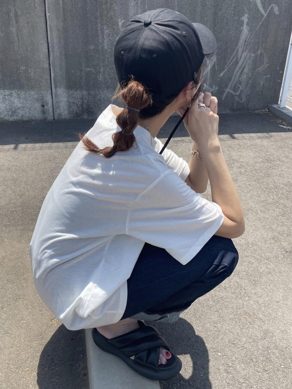 ブルー系のデニムパンツ、ブラック系のサンダル、ホワイト系のTシャツ/カットソーを着用したレディースの夏コーディネートの3枚目の写真