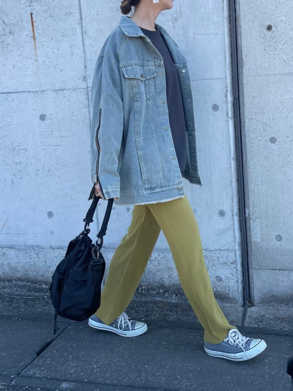 ブルー系のデニムジャケット、ブラック系のメッセンジャーバッグ、グレー系のスニーカーを着用したレディースの春コーディネートの2枚目の写真
