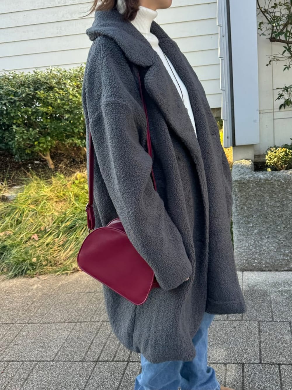 グレー系のその他アウター、ホワイト系のニット/セーター、ブルー系のデニムパンツを着用したレディースの冬コーディネートの4枚目の写真