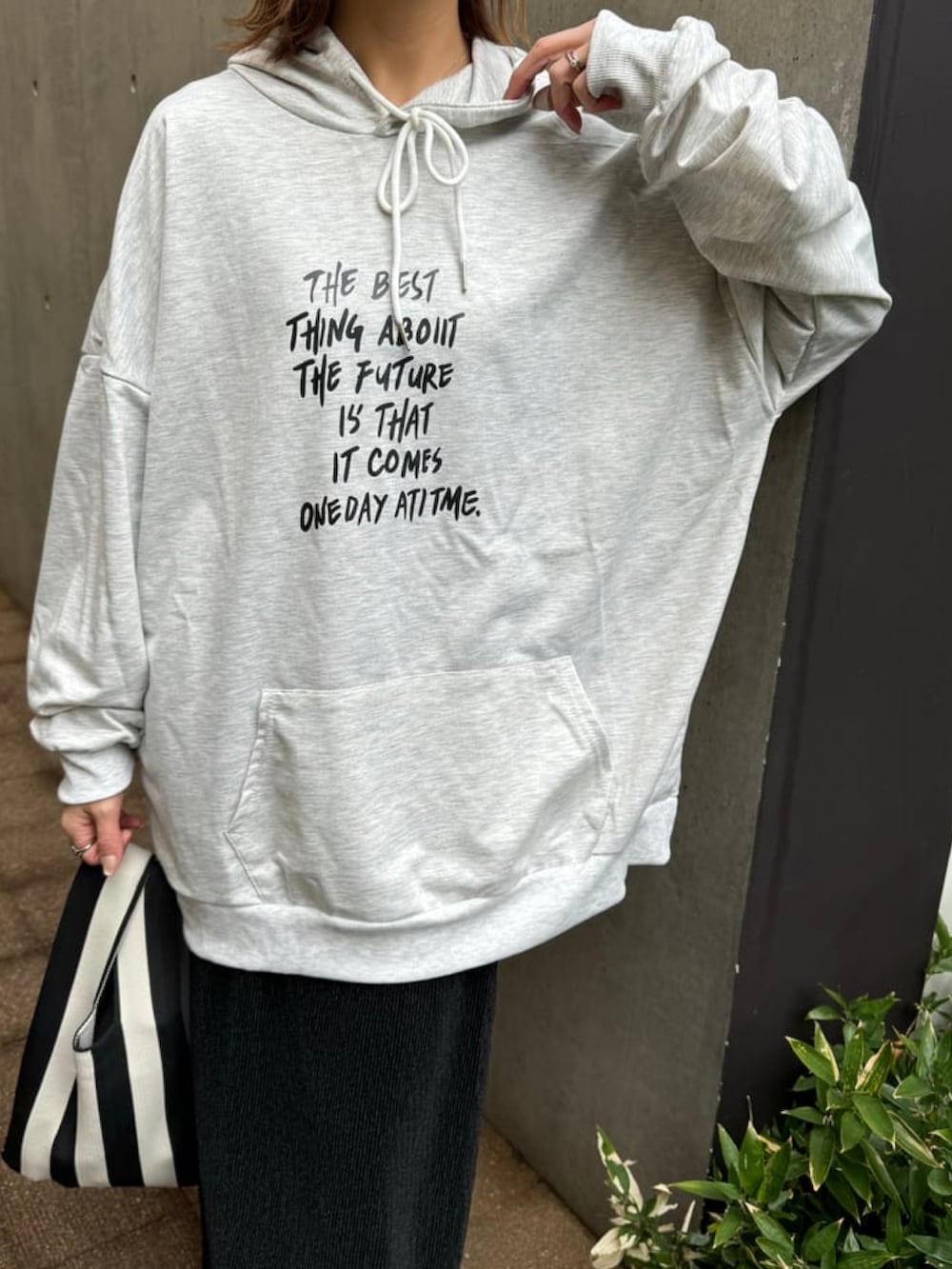 オレンジ系のハンドバッグ、グレー系のパーカー、ブラック系のスカートを着用したレディースの冬コーディネートの4枚目の写真