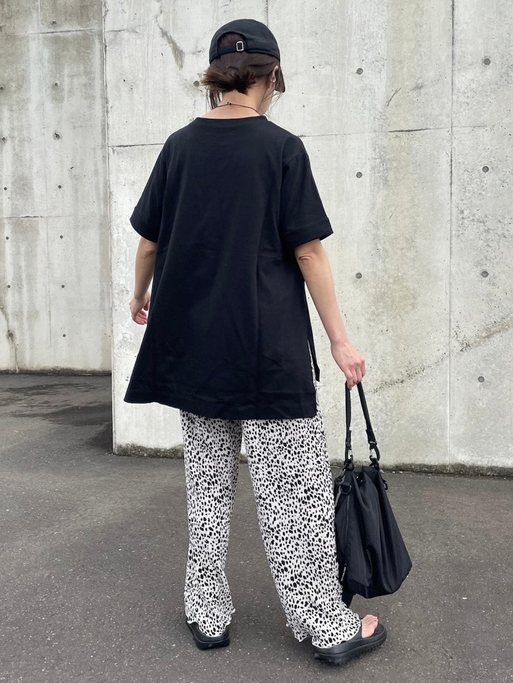 ブラック系のTシャツ/カットソー、ブラック系のメッセンジャーバッグ、ホワイト系のその他パンツを着用したレディースの春コーディネートの4枚目の写真