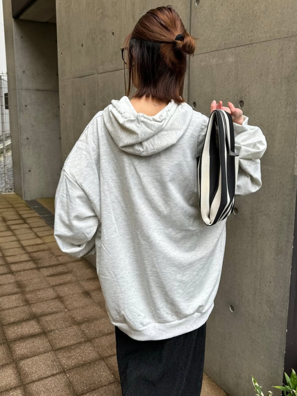 オレンジ系のハンドバッグ、グレー系のパーカー、ブラック系のスカートを着用したレディースの冬コーディネートの5枚目の写真