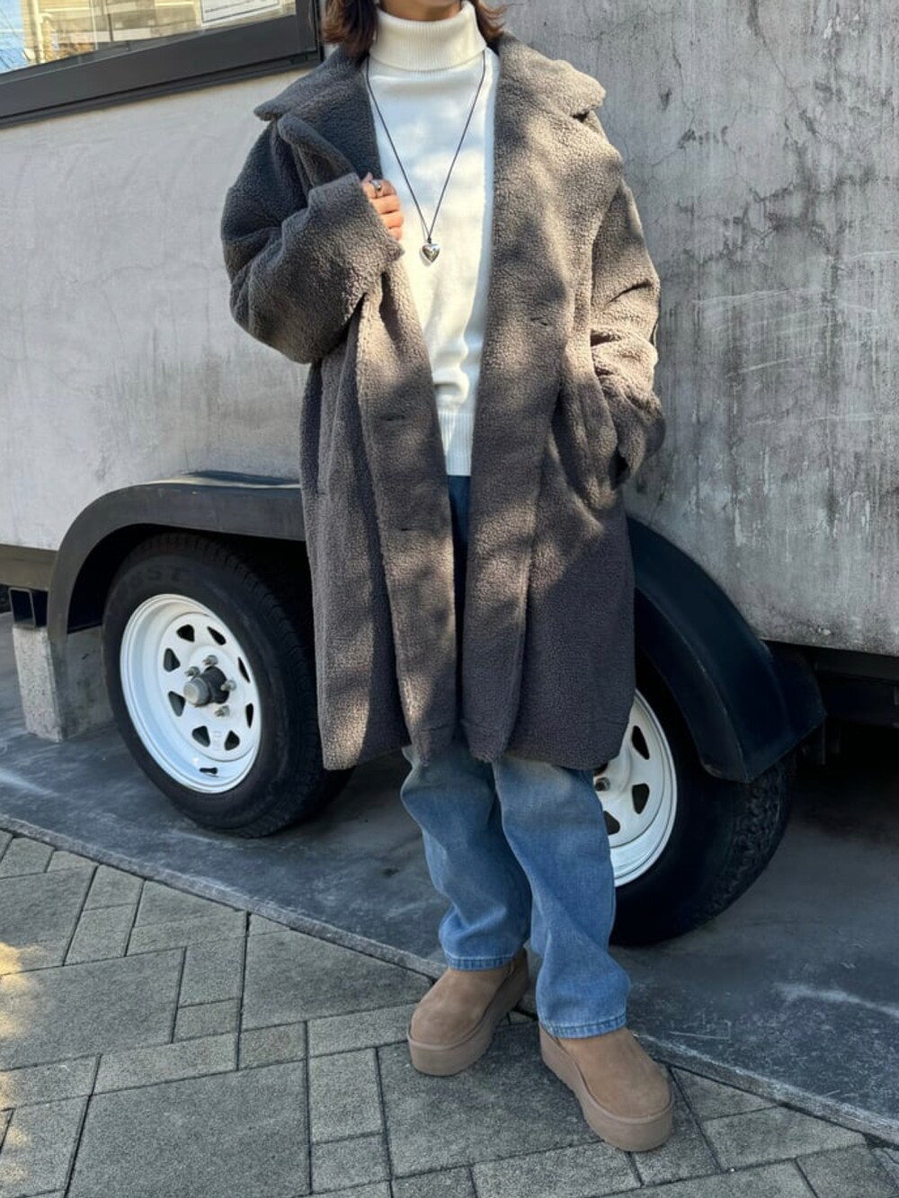 グレー系のその他アウター、ホワイト系のニット/セーター、ブルー系のデニムパンツを着用したレディースの冬コーディネートの2枚目の写真