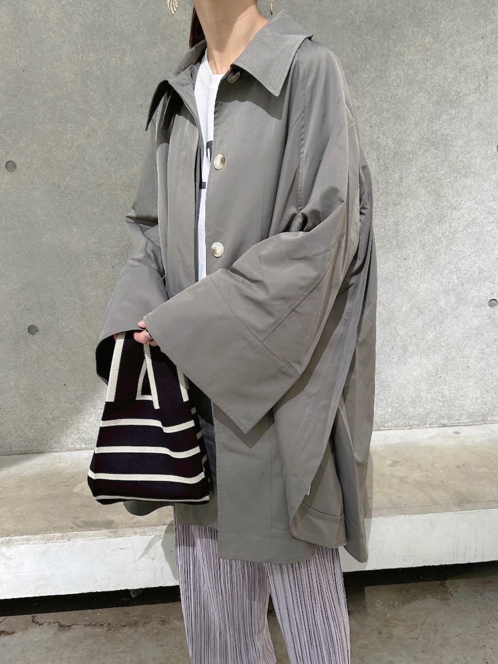 グリーン系のステンカラーコート、パープル系のその他パンツ、グレー系のスニーカーを着用したレディースの春コーディネートの4枚目の写真