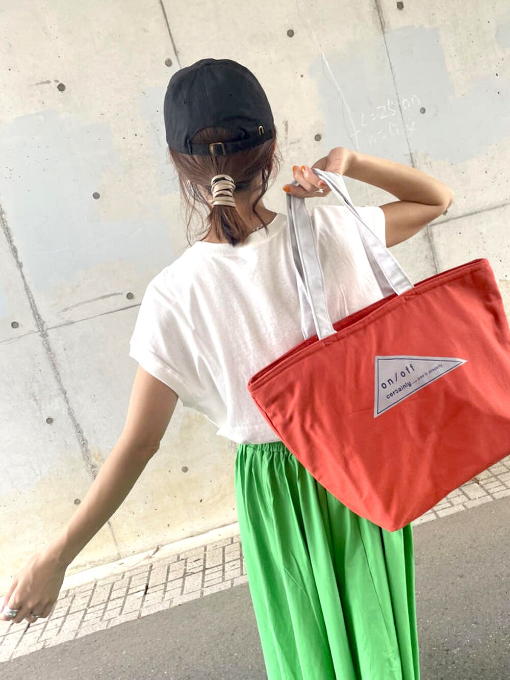グリーン系のスカート、オレンジ系のトートバッグ、ブラック系のスニーカーを着用したレディースの夏コーディネートの5枚目の写真