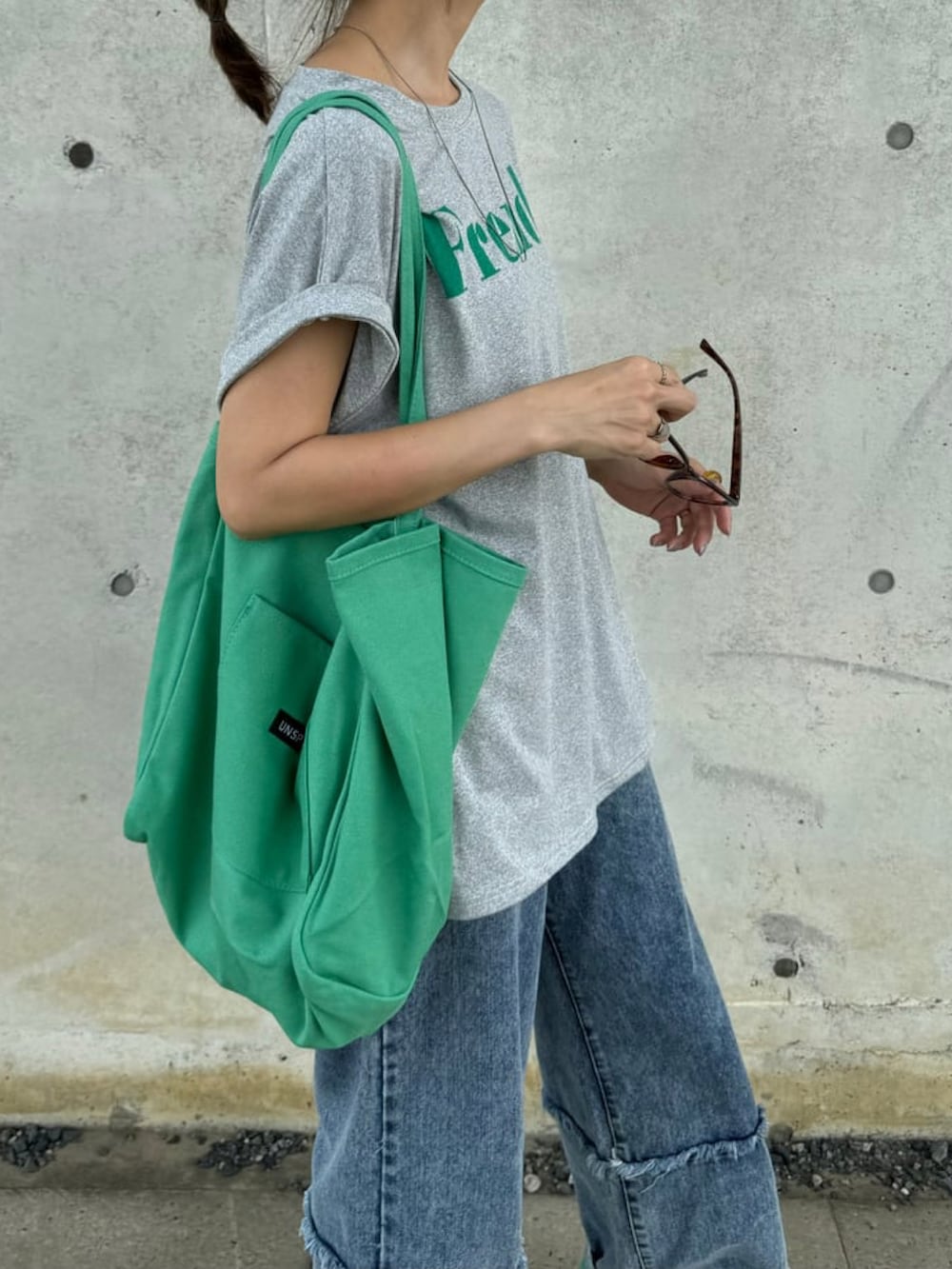 グレー系のTシャツ/カットソー、ブルー系のデニムパンツ、ピンク系のトートバッグを着用したレディースの夏コーディネートの3枚目の写真