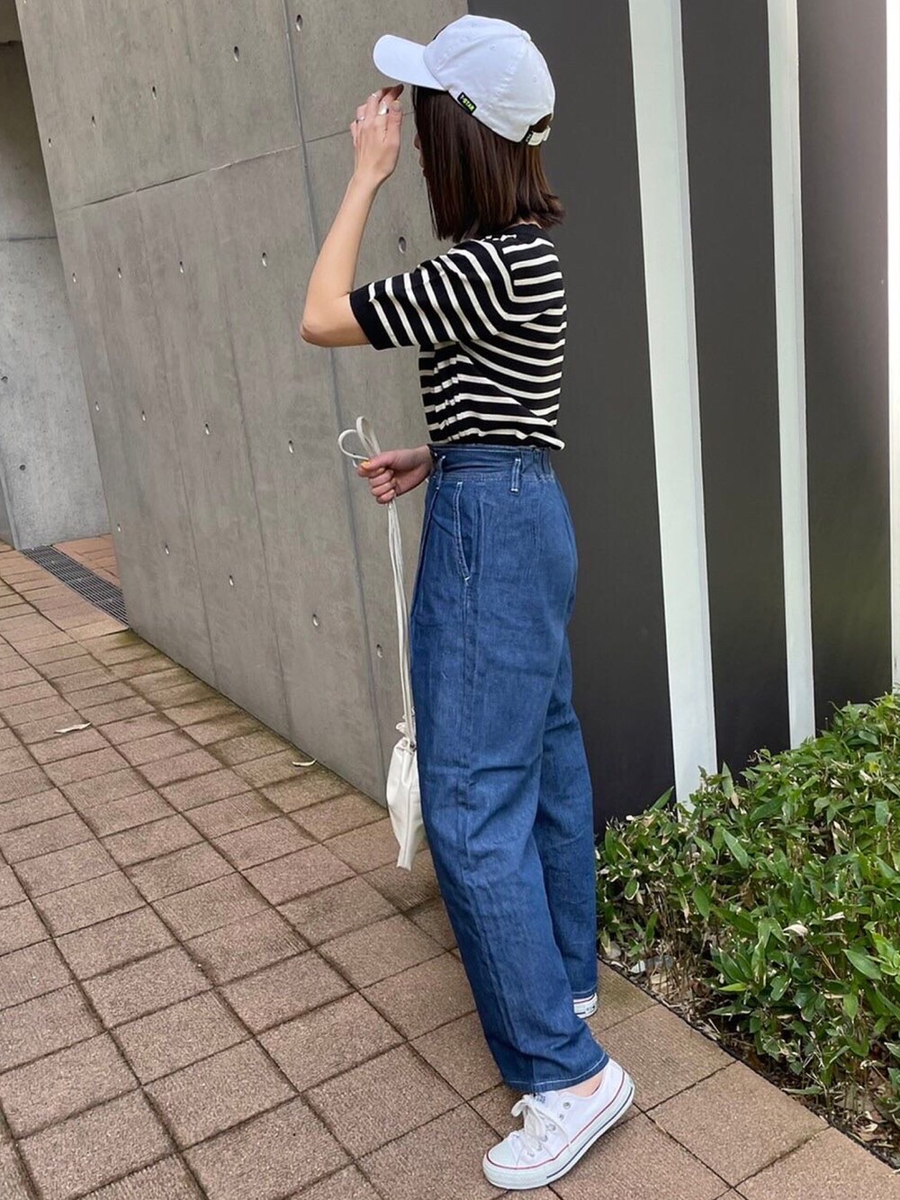 ブラック系のTシャツ/カットソー、ブルー系のデニムパンツ、ホワイト系のスニーカーを着用したレディースの春コーディネートの4枚目の写真