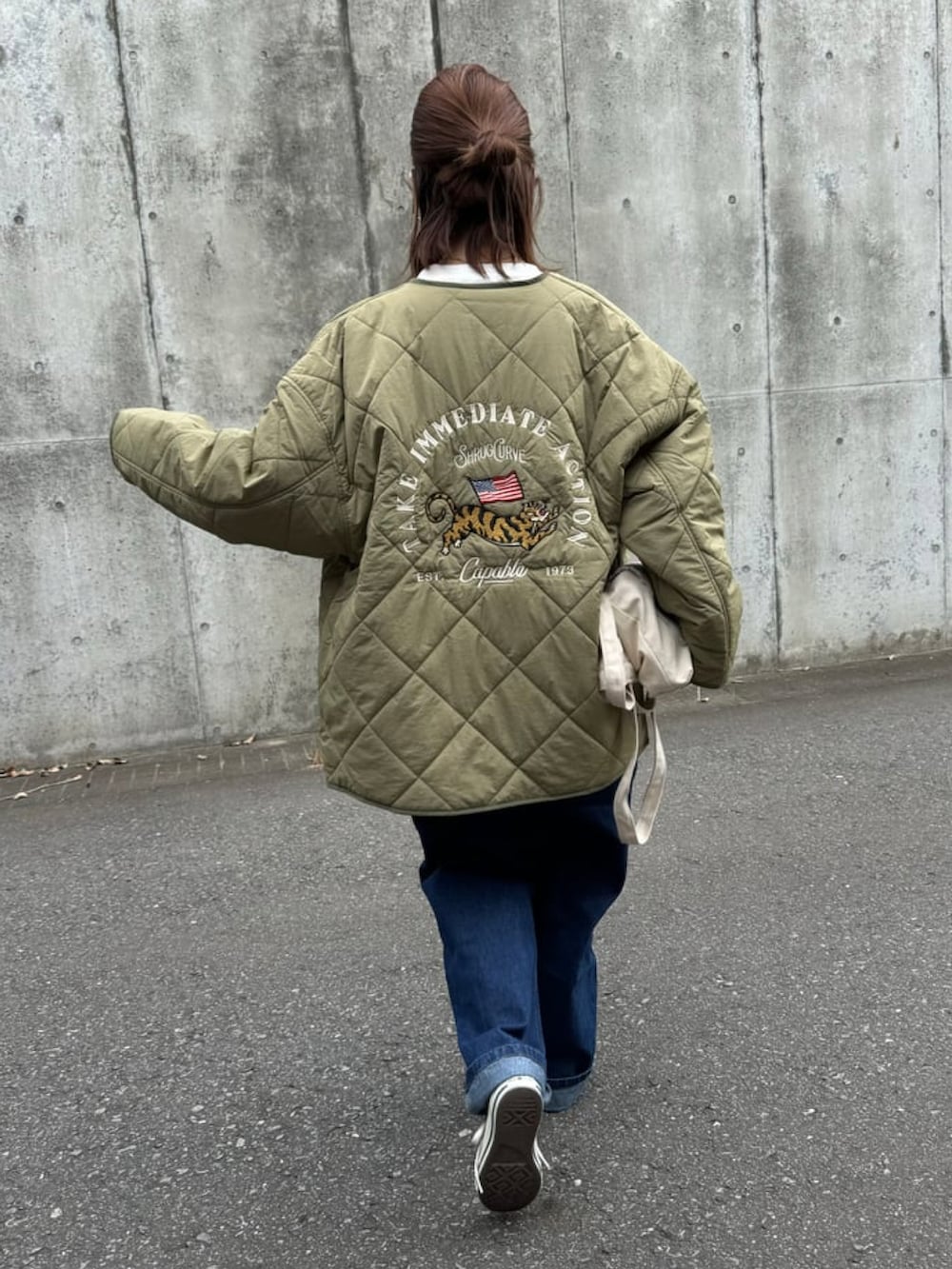 グリーン系のノーカラーコート、ブルー系のサロペット/オーバーオール、ホワイト系のTシャツ/カットソーを着用したレディースの秋コーディネートの2枚目の写真