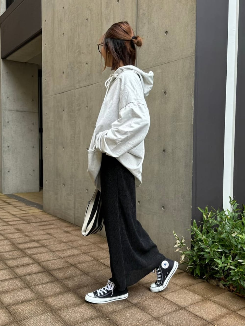 オレンジ系のハンドバッグ、グレー系のパーカー、ブラック系のスカートを着用したレディースの冬コーディネートの2枚目の写真