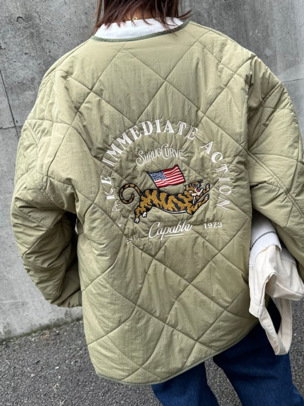 グリーン系のノーカラーコート、ブルー系のサロペット/オーバーオール、ホワイト系のTシャツ/カットソーを着用したレディースの秋コーディネートの5枚目の写真