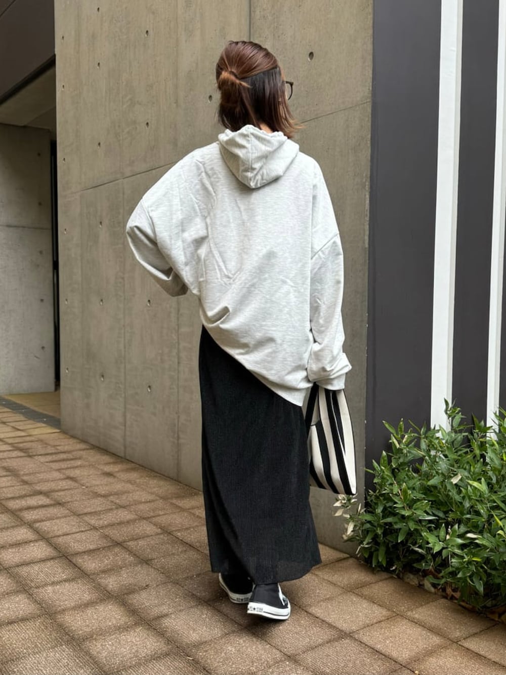 オレンジ系のハンドバッグ、グレー系のパーカー、ブラック系のスカートを着用したレディースの冬コーディネートの3枚目の写真