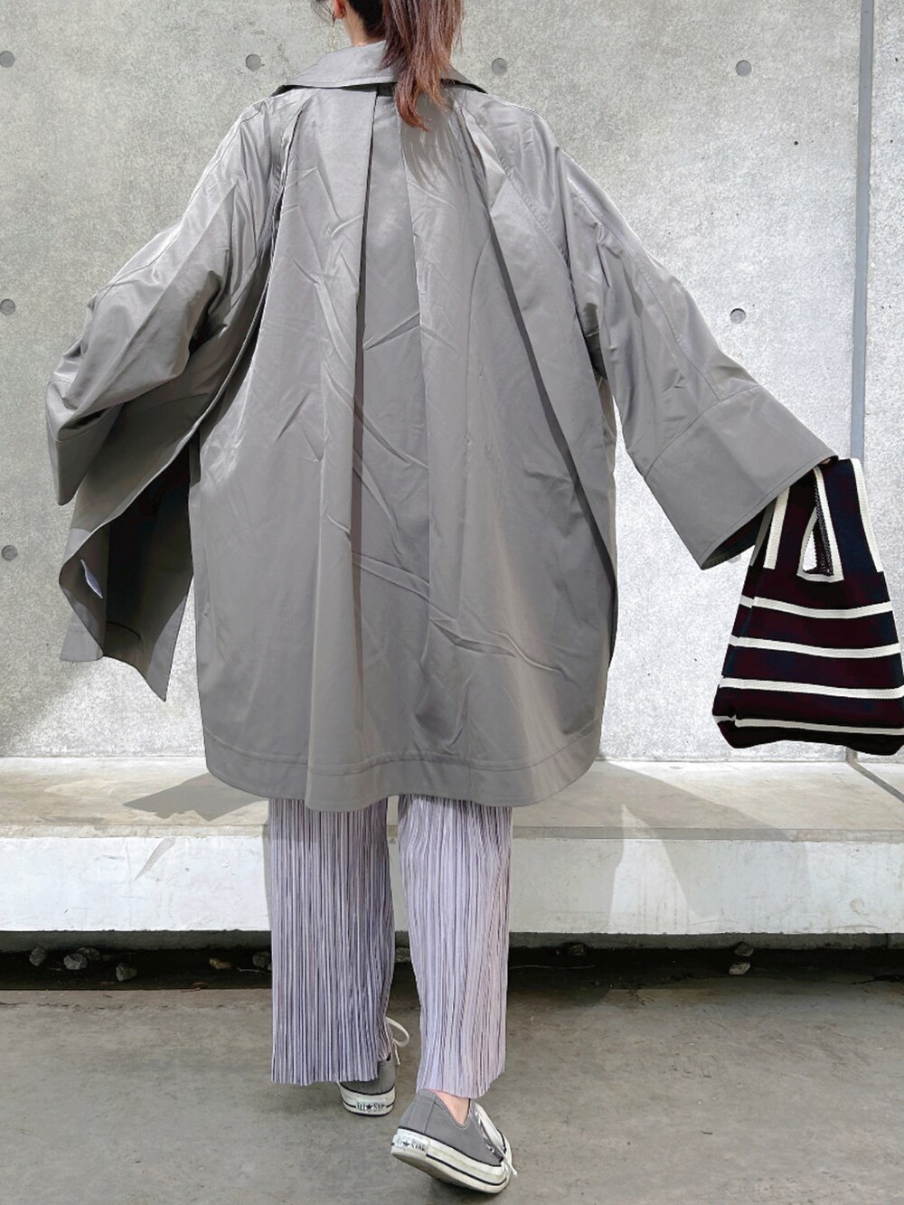 グリーン系のステンカラーコート、パープル系のその他パンツ、グレー系のスニーカーを着用したレディースの春コーディネートの3枚目の写真