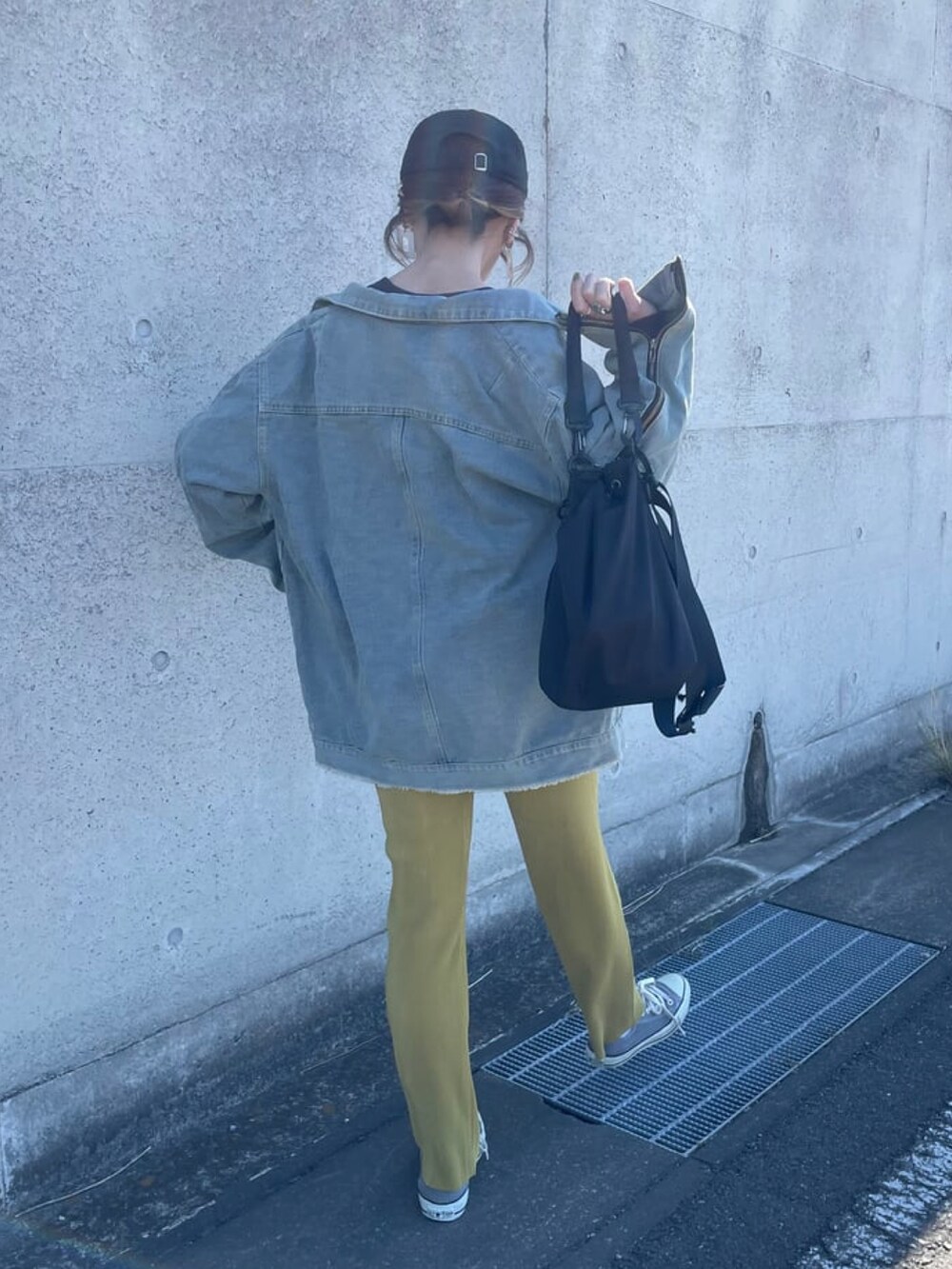 ブルー系のデニムジャケット、ブラック系のメッセンジャーバッグ、グレー系のスニーカーを着用したレディースの春コーディネートの3枚目の写真