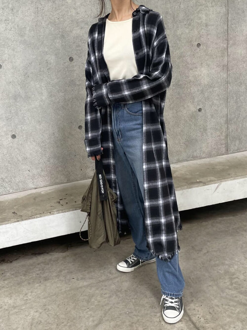 ホワイト系のTシャツ/カットソー、ブラック系のシャツワンピース、ブルー系のデニムパンツを着用したレディースの秋コーディネートの4枚目の写真