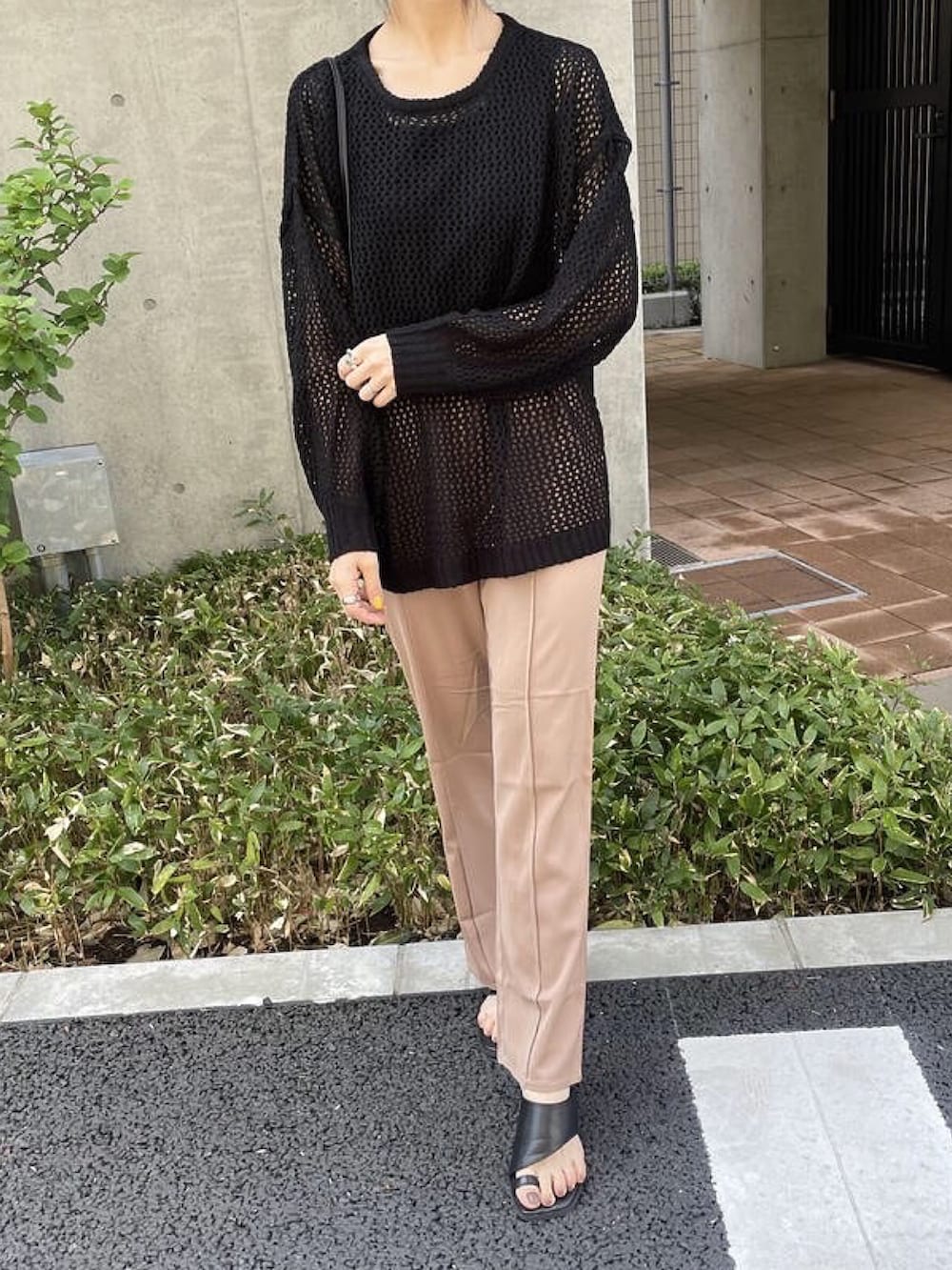 ブラック系のニット/セーター、ブラック系のタンクトップ、ベージュ系のショルダーバッグを着用したレディースの春コーディネートの2枚目の写真